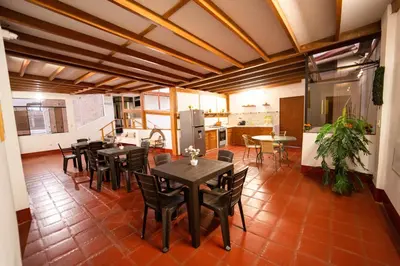 a dining room with tables and chairs and a kitchen at Hostal Los Balcones in Nazca
