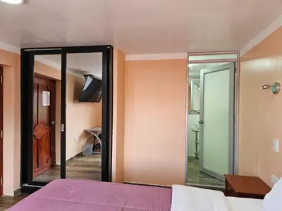 a bedroom with a glass door leading to a shower at Hospedaje Paqcha in Cusco
