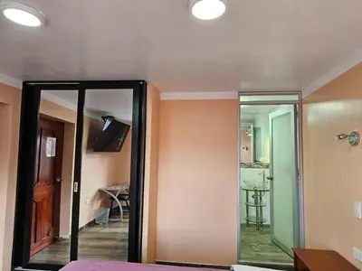 a bedroom with a mirror and a room with a table at Hospedaje Paqcha in Cusco