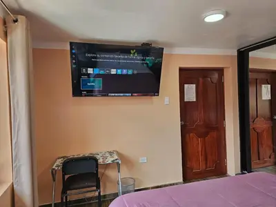 a bedroom with a bed and a television on the wall at Hospedaje Paqcha in Cusco