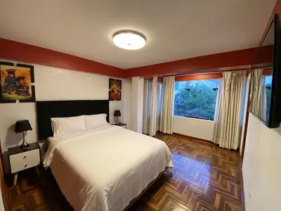 a bedroom with a white bed and a large window at Plaza del Inka in Cusco