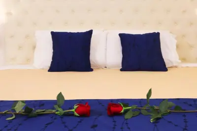 a bed with blue pillows and two red roses on it at Rig Vêda Hotel in Lima