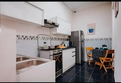 a kitchen with white cabinets and a table and chairs at Tripper Monkey House Miraflores in Lima
