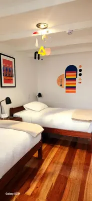 a room with two beds and a surfboard on the wall at Solara Art House Hotel in Cusco