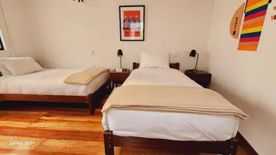 two twin beds in a room with wooden floors at Solara Art House Hotel in Cusco