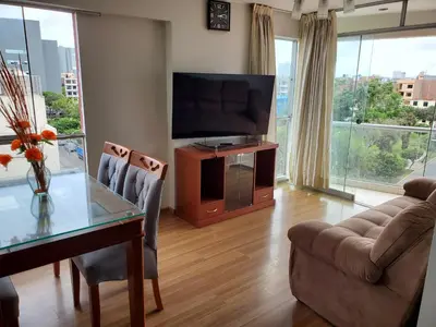a living room with a television and a table with chairs at Edificio Parque Suarez - San Miguel in Lima