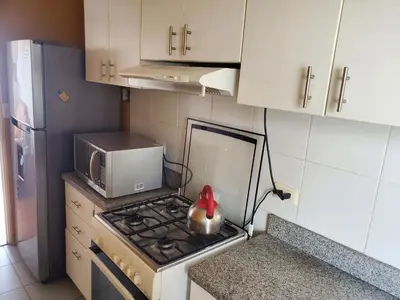 a small kitchen with a stove and a microwave at Edificio Parque Suarez - San Miguel in Lima