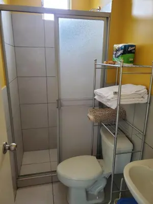 a small bathroom with a toilet and a shower at Edificio Parque Suarez - San Miguel in Lima
