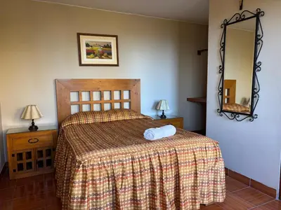 a bedroom with a bed with a blanket and a mirror at Hotel Alicia in El Puente