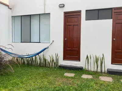 a hammock in front of a house with two doors at Hermosa habitación independiente cerca a Miraflores in Lima