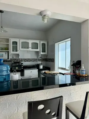 a kitchen with a black counter top with a table at Surfer Hostel El Quilla Punta Hermosa in Punta Hermosa