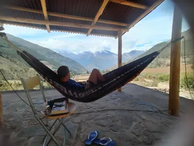 a man sitting in a hammock looking out at the mountains at CASA de SALCANTAY , Choquequirao in Cachora