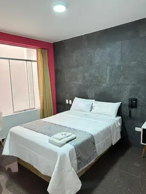 a bedroom with a large bed with white sheets at Hotel Atenas City in San Andrés