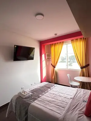 a bedroom with a bed and a tv on the wall at Hotel Atenas City in San Andrés