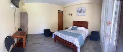 a bedroom with a bed and a table and a desk at DCampos Lodge in Oxapampa