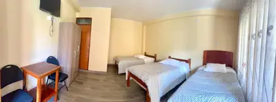 a room with two beds and a table and a desk at DCampos Lodge in Oxapampa