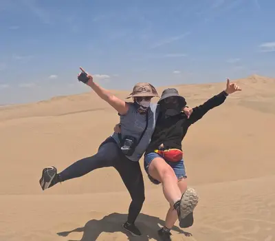 two people jumping in the sand in the desert at Adanny Tours Peru in Lima