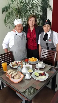 a group of three people sitting at a table with food at Hotel Rivera in Ayacucho