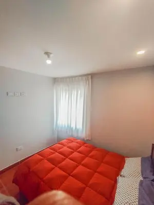 a bedroom with an orange bed in front of a window at Cusco Central Complete Apartment in Cusco