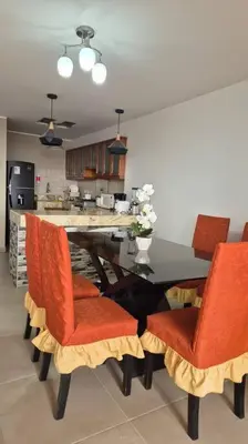 a kitchen with a dining room table with red chairs at Apartamento duplex a 1 cuadra de Playa Naplo in Pucusana