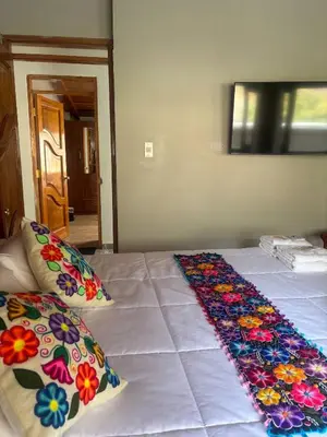 a bed with colorful pillows on top of it at Rumiwasi Inn Apartament in Ollantaytambo