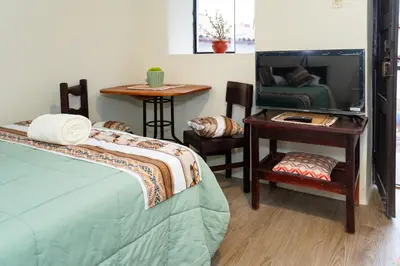 a bedroom with a bed and a table with a mirror at Munay Tika house in Cusco
