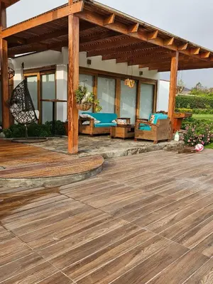 a wooden deck with a pergola and chairs on a house at Alquiler Casa de Campo Asia Cañete in San Andrés