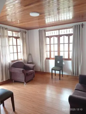 a living room with two couches and a table and windows at Casa Las Palmeras in Oxapampa