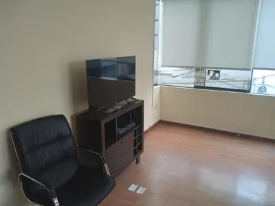 a living room with a chair and a television at Departamento Centro Financiero San isidro in Lima