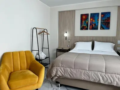 a bedroom with a bed and a yellow chair at Residencial Mar Caribe in Lima