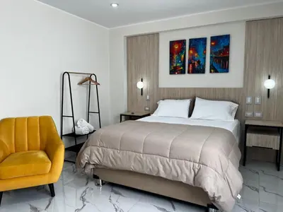 a bedroom with a large bed and a chair at Residencial Mar Caribe in Lima