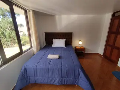 a bedroom with a bed with a blue comforter and two windows at Casa de Campo Apu San Isidro in Urubamba