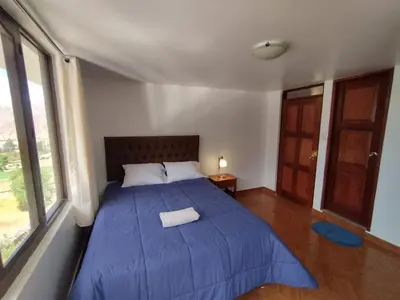 a bedroom with a bed with a blue comforter at Casa de Campo Apu San Isidro in Urubamba