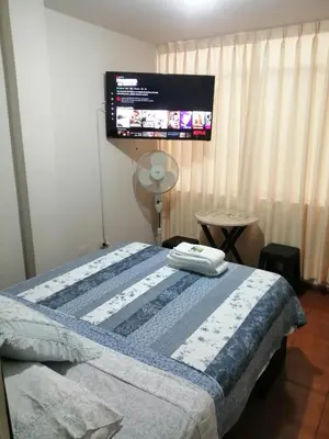 a bedroom with a bed with a tv on the wall at Lopez House Family Aparment in Lima
