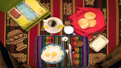 a table topped with a plate of eggs and bread at Beraja Family Hostel in Lima