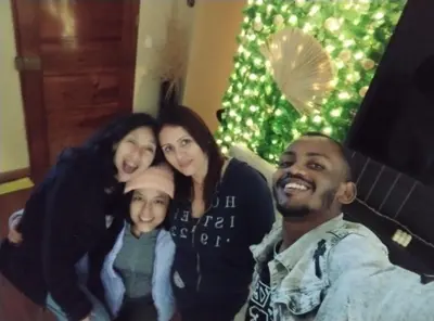 a family posing for a picture in front of a christmas tree at Sai in Lima