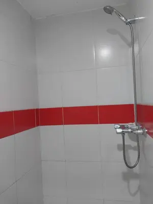 a shower in a bathroom with a red and white wall at Amplio Departamento amoblado, Condominio Parques de la Huaca - San Miguel in Lima
