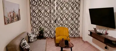 a living room with a yellow chair and a flat screen tv at Warmisitay Mini departamento in Lima