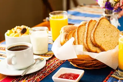 a table with a basket of bread and a cup of coffee at La Rosa Wellness Lodge in Urubamba