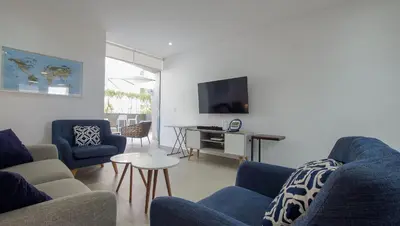 a living room with blue couches and a tv at Condominio Ocean reef in San Bartolo