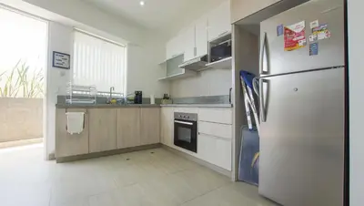 a white kitchen with a refrigerator and a window at Condominio Ocean reef in San Bartolo