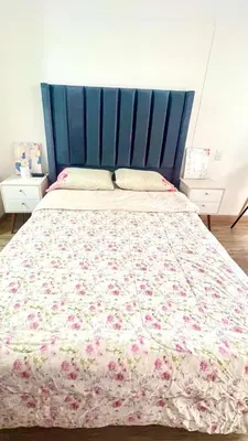 a bed with a blue headboard and a floral bedspread at Pacific apartamento Miraflores in Lima