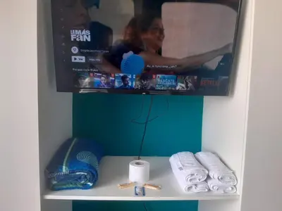 a tv sitting on top of a shelf with towels at San Miguel Rooms Lima Airport B&B in Lima