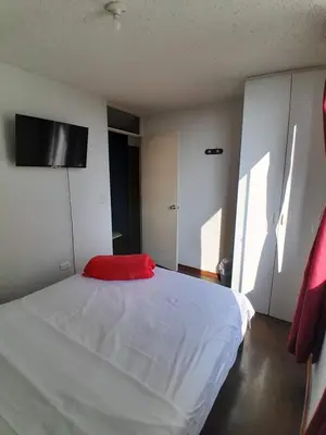a bedroom with a white bed with a red pillow at San Miguel Rooms Lima Airport B&B in Lima