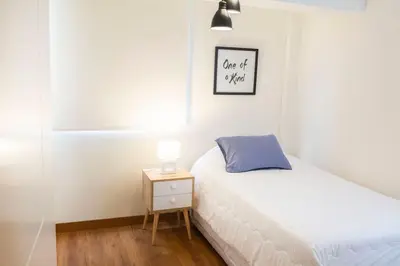 a small bedroom with a bed and a night stand at Comfort and Space 3bed and 2 and haf bath centric location in Lima