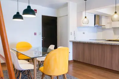 a kitchen with a glass table and yellow chairs at Comfort and Space 3bed and 2 and haf bath centric location in Lima