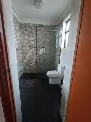 a bathroom with a toilet and a glass shower at Eli Travelers House in Lima