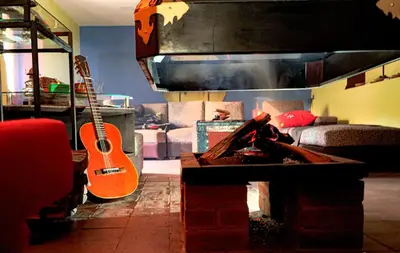 a living room with a guitar and a fire place at Casa Jazmín Hospedaje Familiar Eco Amigable - Huayoccari, Sacred Valley in Huayoccare