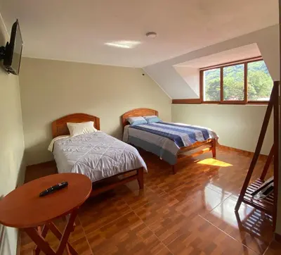 a bedroom with two beds and a table in it at LagunaNegra Oxapampa in Palmira