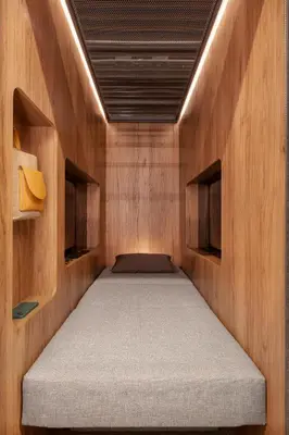 a small room with a bed in a wooden room at Sleepover - Lima Airport, the only in-terminal sleep pods in Lima